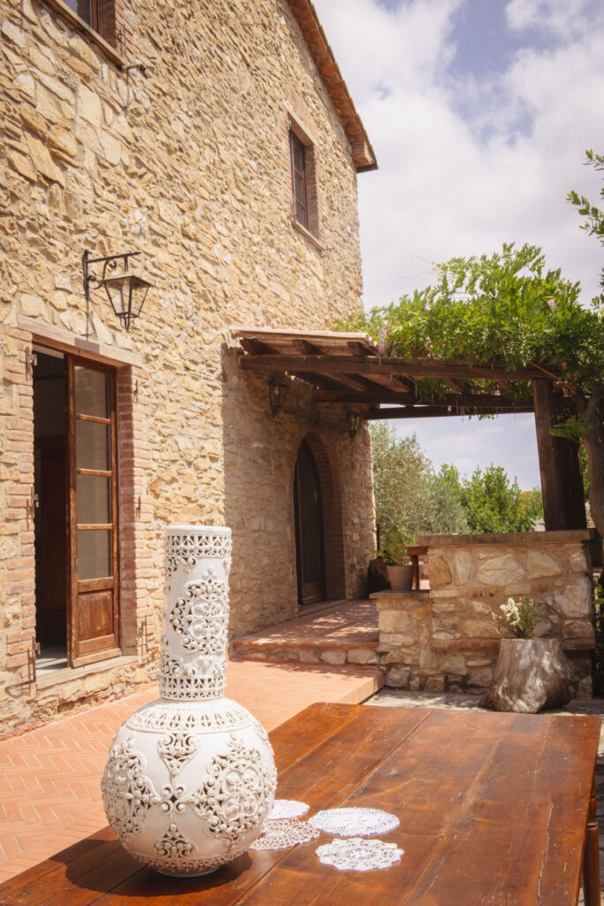 casa in pietra con portico e vaso bianco decorato in pietra su un tavolo in legno