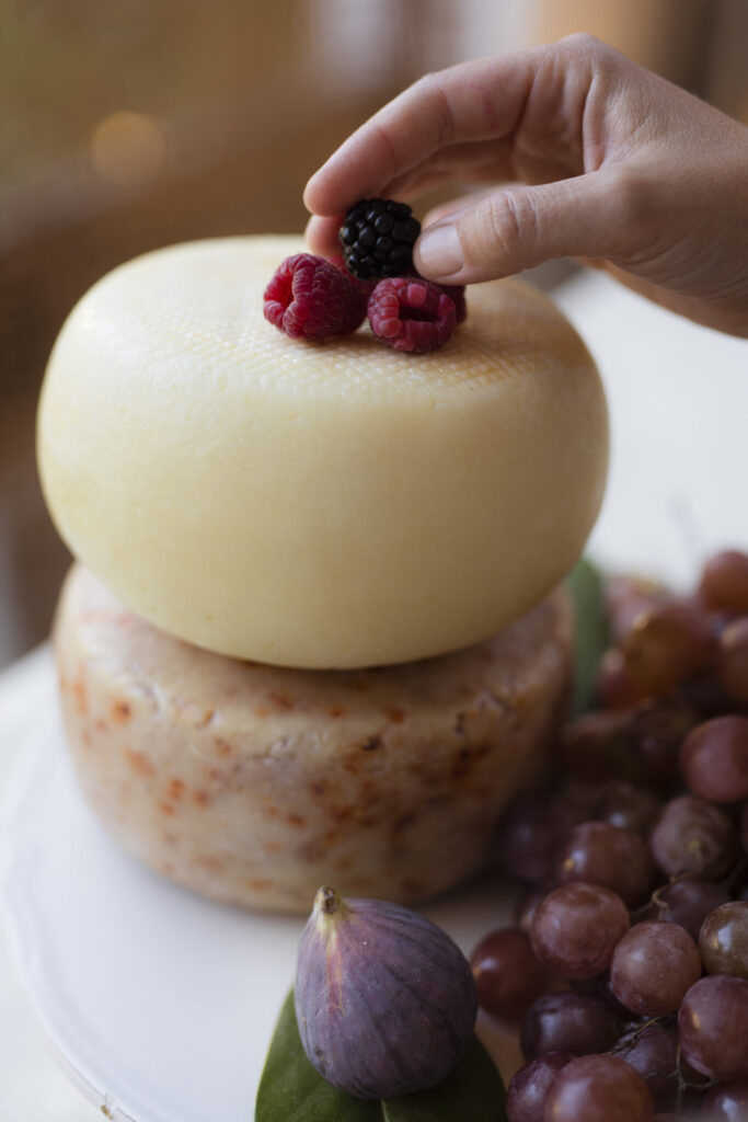mano che pone frutti di bosco su due forme di formaggio
