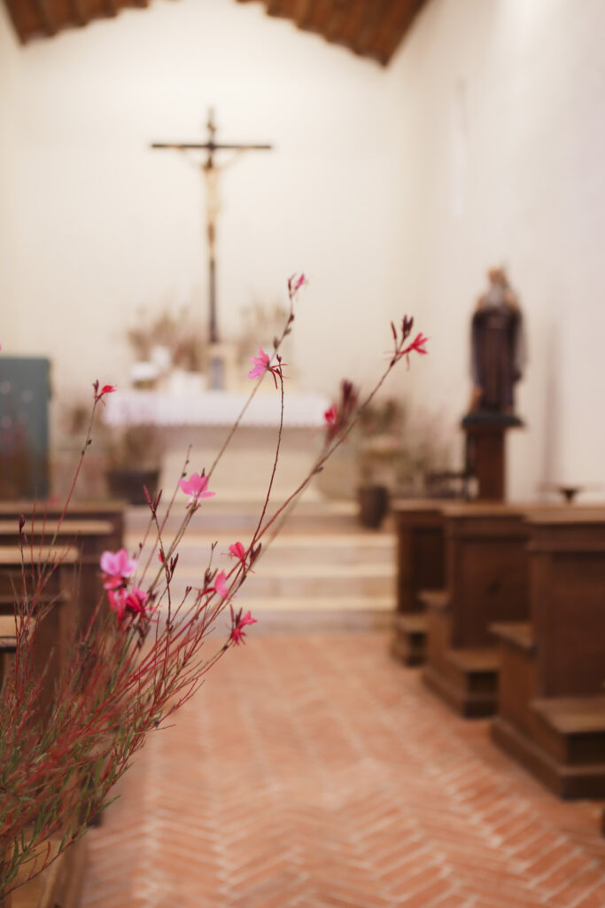 interno di una piccola chiesa sfuocato con primo piano di fiori rosa e rossi